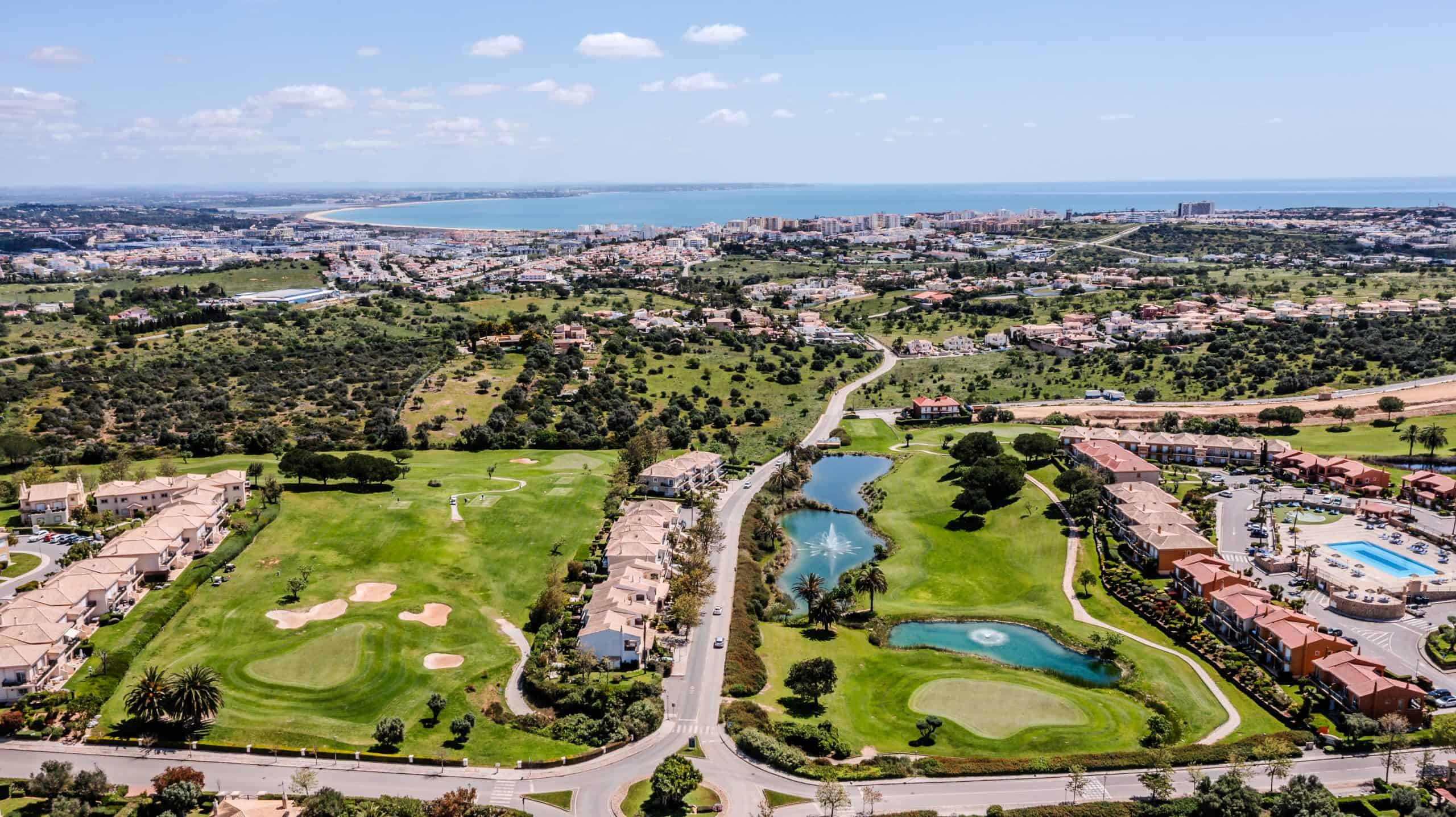 Luxurious golf course community near ocean with scenic views, lush green fairways, water features, residential townhomes, and recreational amenities, ideal for upscale living and investment.